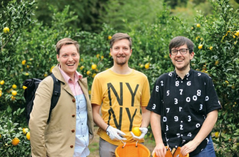 Three founders of Yuzu Kyodai stand, smiling, surrounded by yuzu trees