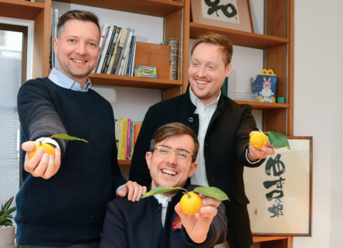 Three founders of Yuzu Kyodai smile to camera and hold yuzu fruits