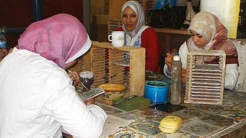 A group of women painting traditional tiles by hand