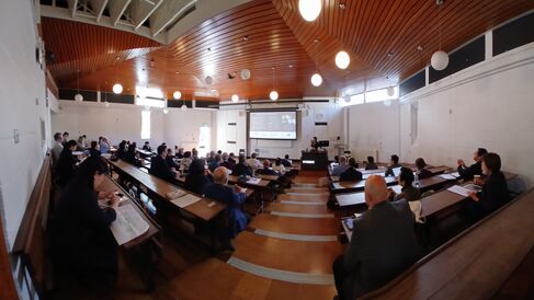 People listening to a lecture and watching a screen in a lecture hall