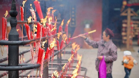 Person burning incense and candles at the Baoguo Temple in Mount Emei, Sichuan province, China