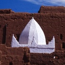 A traditional mud-brick building with a white dome, characteristic of architecture found in North Africa, particularly associated with the Almoravid and Almohad dynasties